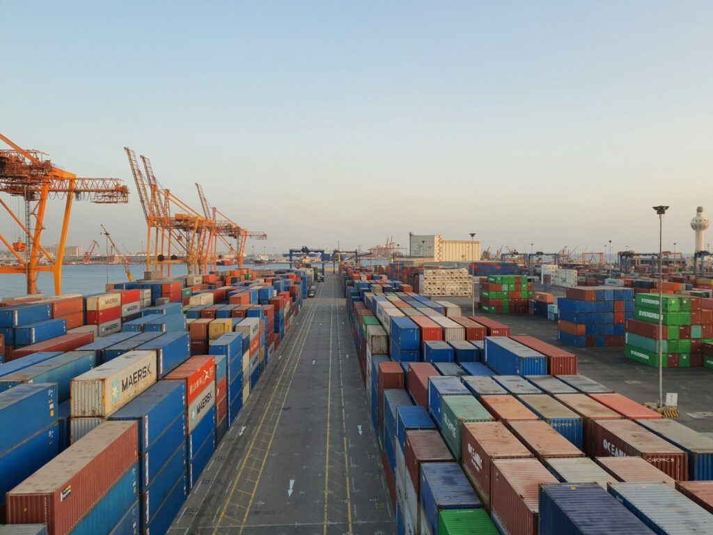 Porto commerciale con container all'alba: le merci importate nell'UE ora pagano la CO2 con il CBAM