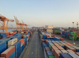Porto commerciale con container all'alba: le merci importate nell'UE ora pagano la CO2 con il CBAM