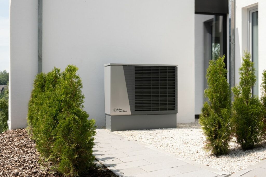 Unità esterna di una pompa di calore sulla parete di una casa, tra le tecnologie finanziabili con la clausola energetica UE