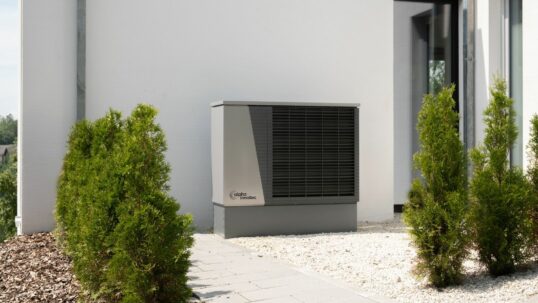 Unità esterna di una pompa di calore sulla parete di una casa, tra le tecnologie finanziabili con la clausola energetica UE