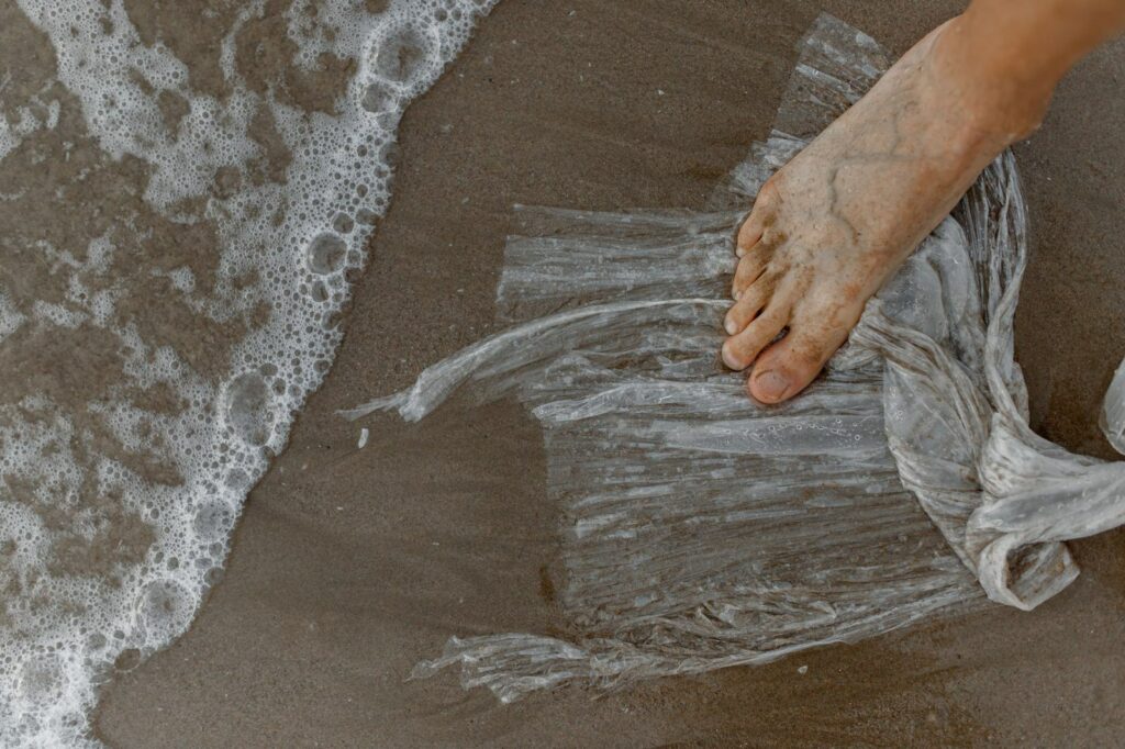 Impronta ecologica: un piede scalzo sulla plastica su una spiaggia