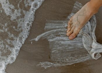 Impronta ecologica: un piede scalzo sulla plastica su una spiaggia