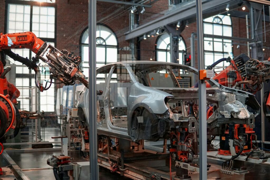 Analisi del ciclo di vita (LCA): carrozzeria di un'auto in fabbrica tra i bracci robotici