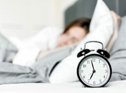 Ora legale permanente: una sveglia sul comodino accanto a una persona che dorme al mattino