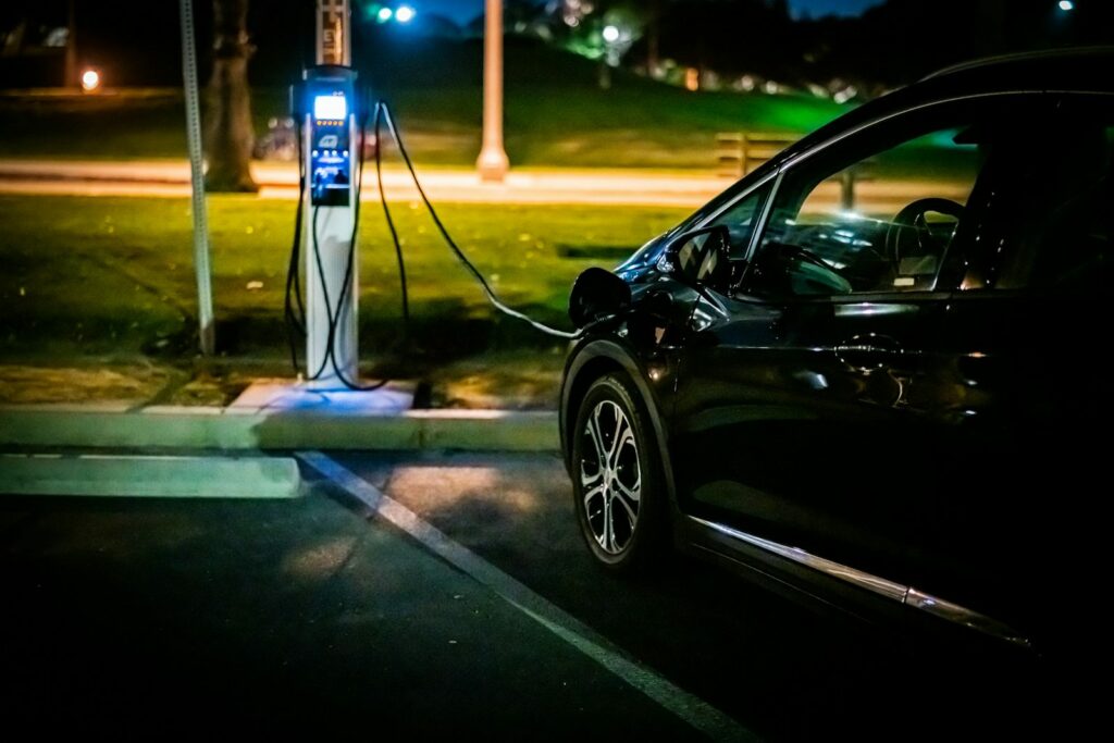 Rete elettrica e auto elettriche: un'auto in ricarica a una colonnina di sera, nelle ore di punta dei consumi