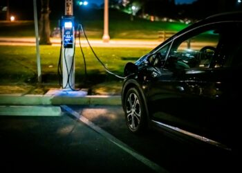 Rete elettrica e auto elettriche: un'auto in ricarica a una colonnina di sera, nelle ore di punta dei consumi