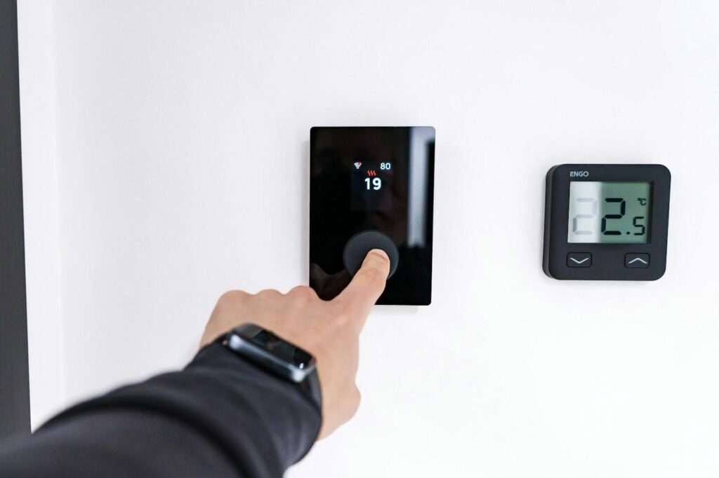 Smart home: una mano regola un termostato smart a parete per controllare il riscaldamento di casa